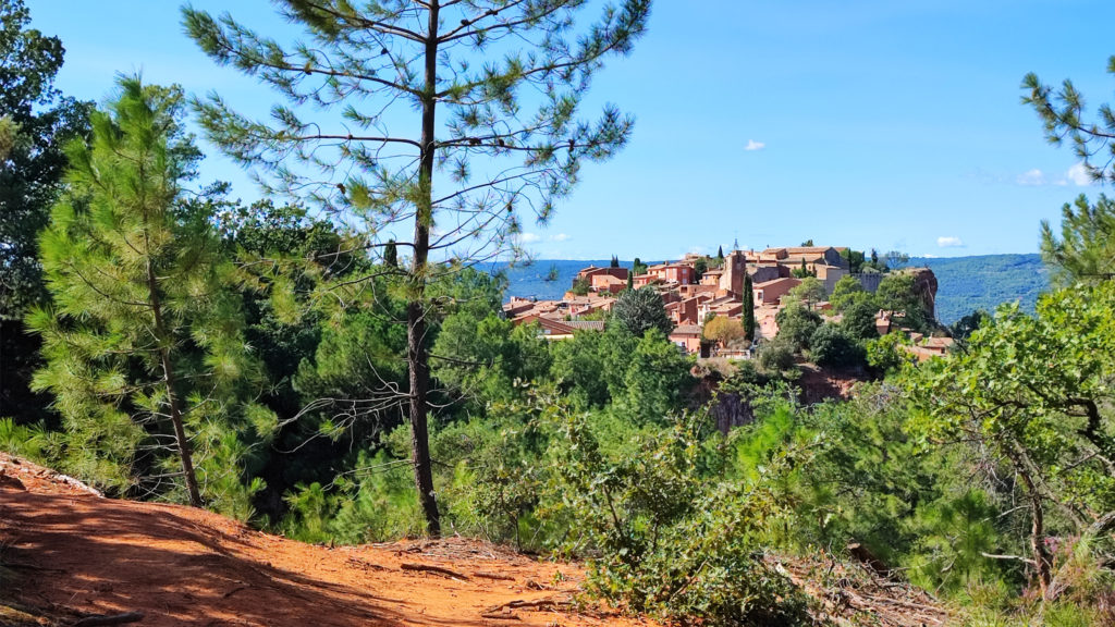 Vue d'un paysage ensoleillé avec végétation verdoyante et un joli village provençal en arrière plan